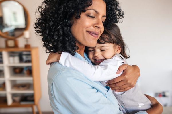 Mother hugging her young daughter in an apartment